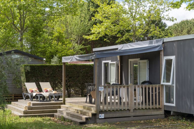 Mobil-home avec terrasse en bois et transats.