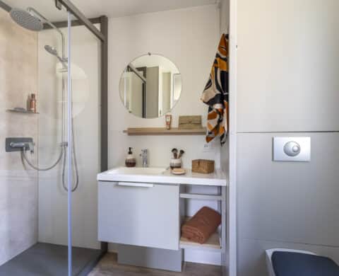 Salle de bains moderne avec douche et lavabo.
