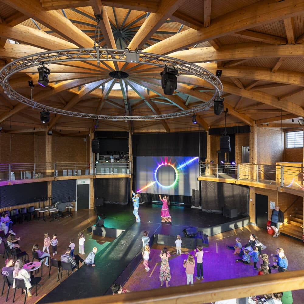 Spectacle interactif pour enfants dans une salle en bois.